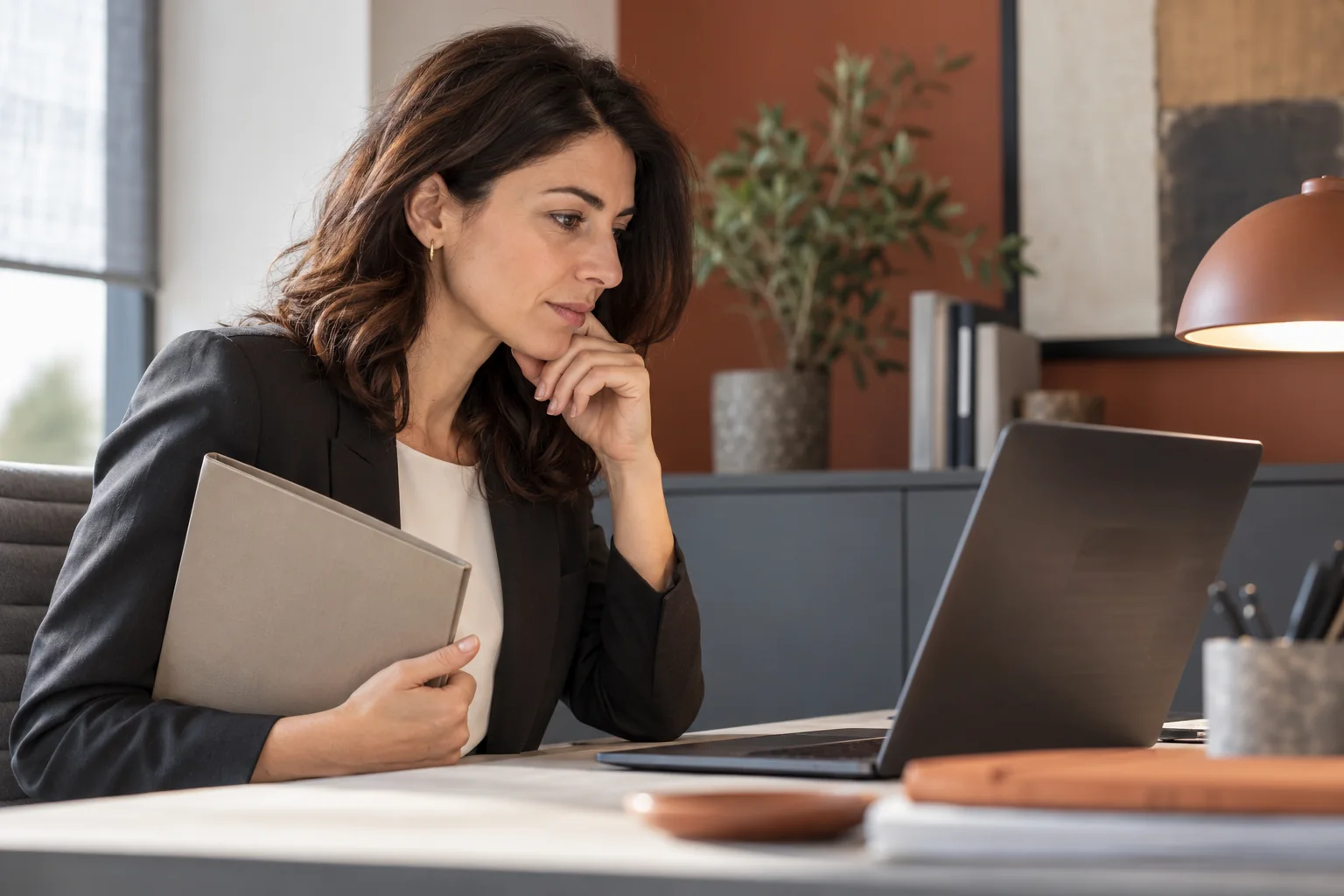 Una responsabile controlla con discrezione una recensione sul portatile in ufficio, senza dati personali leggibili sullo schermo.