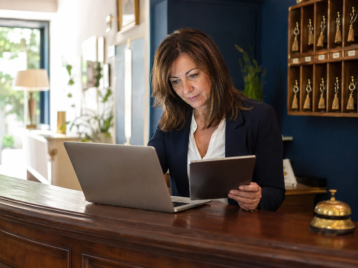 Responsabile di un hotel consulta un tablet e un computer al banco della reception